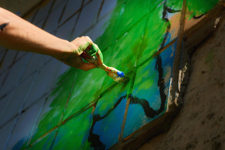 Female artist's hand with a brush painting graffiti on the wallの写真素材