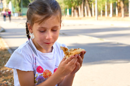 Snack. Cute grimy child girl eating a piece of pizzaの写真素材