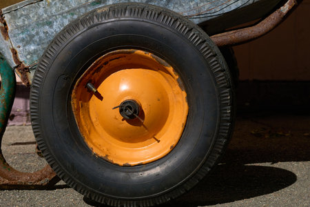 a small cart with a single wheel at the front and two supporting legs and two handles at the rearの写真素材