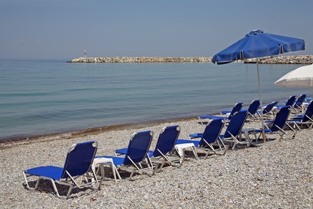Greece, reed umbrellas and blue sunbeds on the beachの写真素材
