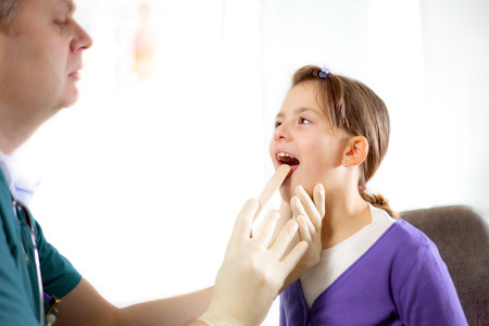 Pediatrician checking little girl throatの写真素材
