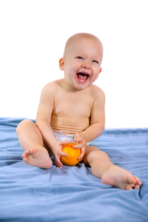 cute one year baby boy holding a orangeの写真素材