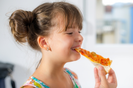 little girl eating pizza の写真素材