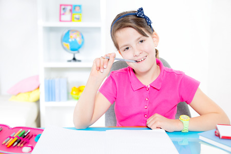 Smiling Caucasian girl doing homework at home の写真素材