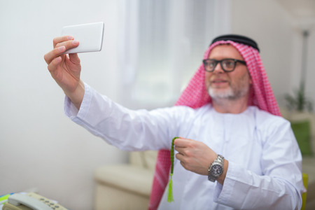Arabian business man in his home office using smart phoneの写真素材