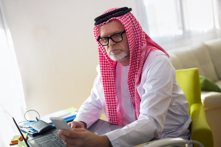 Arabian business man in his home office using smart phoneの写真素材