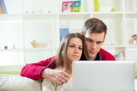 Young couple relaxing on sofa with laptop in the living room.Selective focusの写真素材
