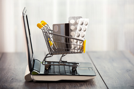 Shopping trolley sitting on open laptop, tablets and credit card in a supermarket trolleyの写真素材