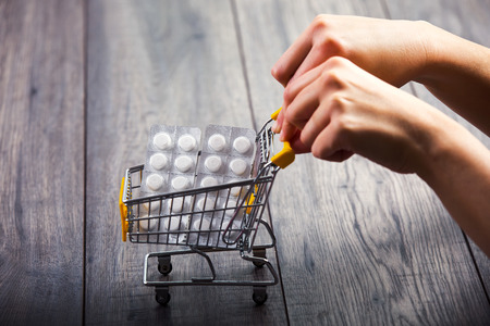 Hands pushing supermarket trolleys filled with pillsの写真素材