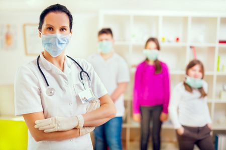 Female doctor and patient teenagers looking at camera, wear protective masks.Medical examination.の写真素材