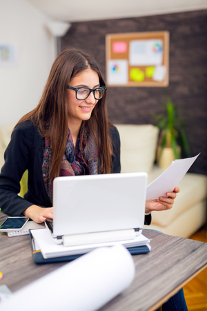Young businesswoman sitting at her desk in the office doing paperworkの写真素材