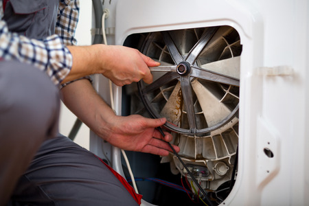 Handyman fixing a washing machine in the kitchenの写真素材