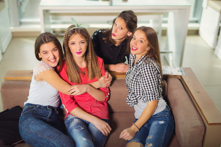 Portrait of four young women sitting at the table in the cafe, selective focusの写真素材