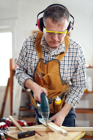 Carpenter working with a saw in his workshopの写真素材