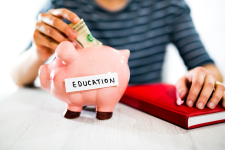 Saving concept. Women's hand puts money in piggy bank. Selective focus. Saving for a educationの写真素材