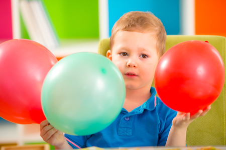 Joyful kid boy on birthday party holding ballonsの写真素材