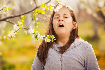 Girl having allergy outdoor. The girl sneezes. Selective focusの写真素材