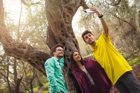 Three young people make selfie under the olive treeの写真素材