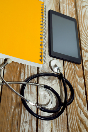 Doctor workplace with blank tablet and stethoscope on wooden backgroundの写真素材