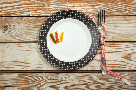 Pasta with tape measure over plate on wooden tableの写真素材