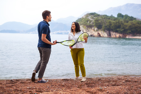 Two young people with tennis racquets on the seashoreの写真素材