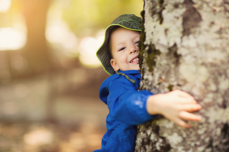 Young boy hugging a treeの写真素材