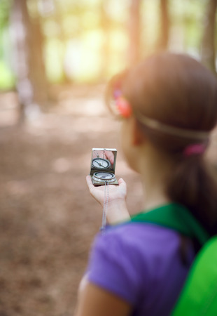 Hiker girl searching direction with a compass in the forestの写真素材