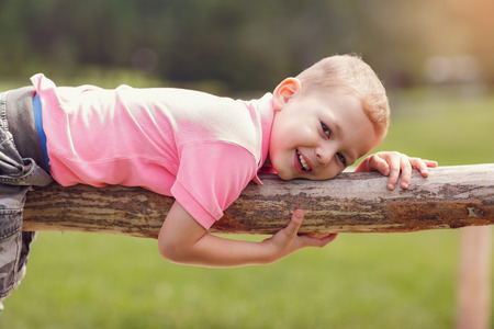 Boy lying on a wooden fenceの写真素材