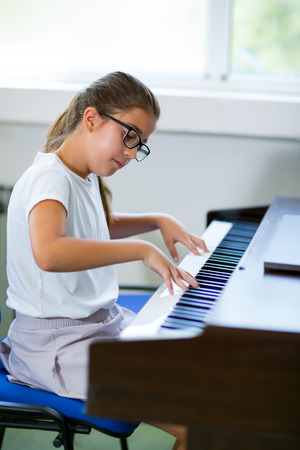 Beautiful girl playing the piano at the music school, selective focusの写真素材