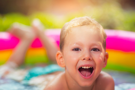 Little boy in inflatable swimming pool outdoor, having funの写真素材