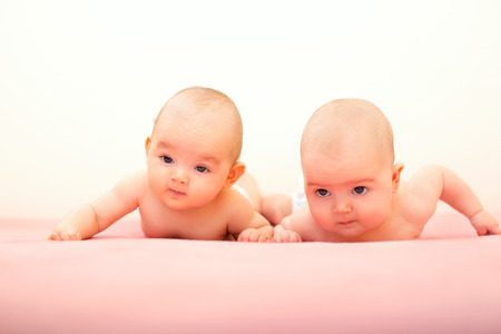 twins girls lying on his stomach on the bedの写真素材