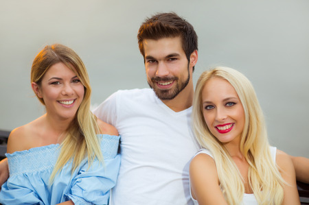 Three friends having fun on the benchの写真素材