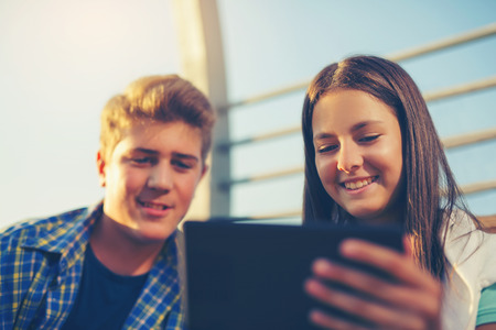 Teenages Girl And Boy On Bench Using Digital Tabletの写真素材
