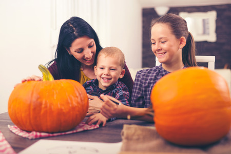 Mother with daughter and son creating big orange pumpkinの写真素材