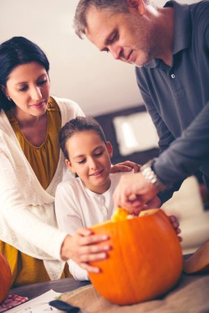 Mother, father and daughter carving pumpkinの写真素材