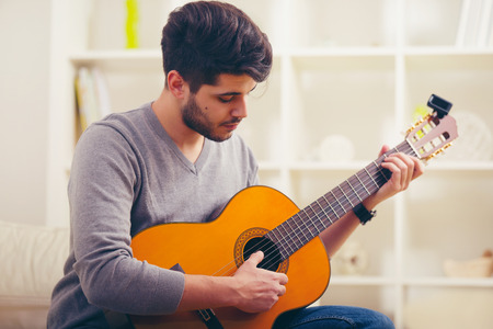 Young man playing guitar and composing a songの写真素材