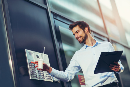 Portrait of a young happy businessman outside the office building, enters the building