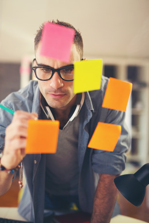 Business man writing on stickers at officeの写真素材