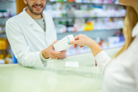Experienced pharmacist counseling female customer in modern pharmacyの写真素材