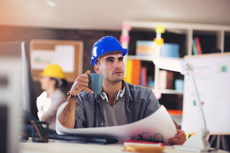 Male architect studying plan in officeの写真素材