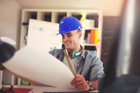 Male architect studying plan in office