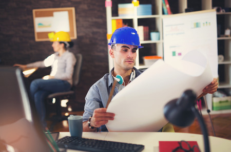 Male architect studying plan in office