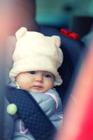 Adorable little girl sitting in car in winter clothesの写真素材