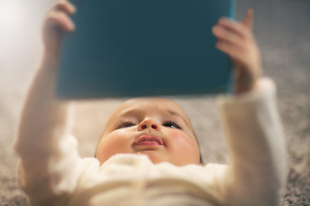 Baby reading a book on backの写真素材