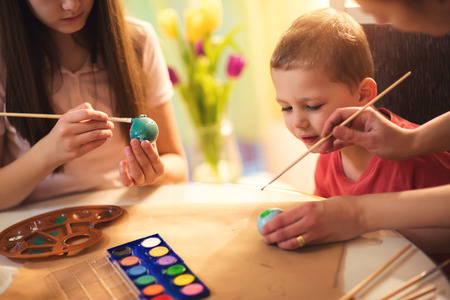 Children paint Easter eggs at homeの写真素材