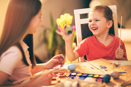 Brother and sister painted Easter eggs at the tableの写真素材