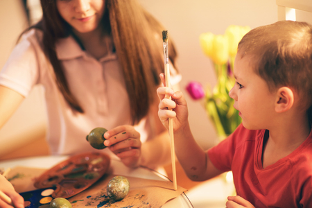 Brother and sister painted Easter eggs at the tableの写真素材