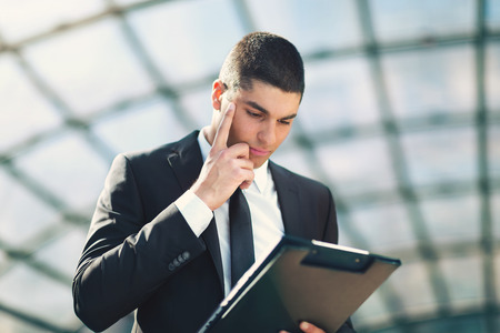 Young businessman review the documentation before work in front of the office buildingの写真素材