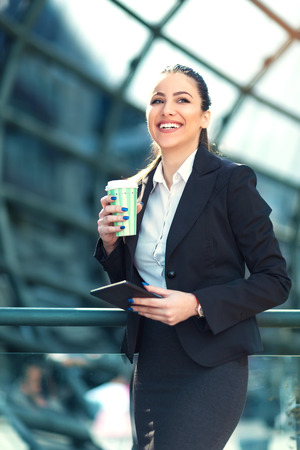 Young businesswoman drinking coffee while holding a digital tabletの写真素材
