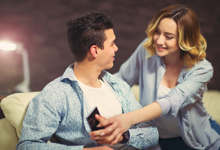 Couple has a problem. Woman wants to take the phone to her husbandの写真素材